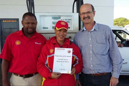 Schalk  Strauss (regs),  bestuurder  van  Birkenhead  Motors,  oorhandig  ‘n kontantprys  en  sertifikaat  aan  Christine Bester.   Claude  Vanqa,    area-bestuurder van Shell staan by.