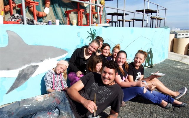 ‘n Deel van die groep jongelinge wat twee lang mure by De Seemans Taphuis verlede Saterdag met verf betakel het – maar wel op ‘n kunstige wyse met ‘n skilderagtige resultaat. Voor lê die groep se “hoofman”, TJ Nortje.