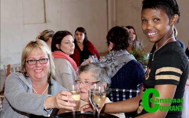 Mandy Phillips (regs) bedien vonkelwyn aan Ria van der Merwe van Kleinbaai.  Adéle Eksteen sit agter.