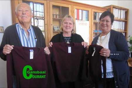 Onderskeidelik links en regs is John en Ivy van Huyssteen van die Gansbaai Lions Klub, wat twintig skooltruie aan me. Haxton (middel) van laerskool Okkie Smuts oorhandig het.