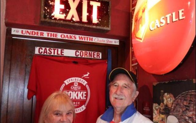 David MacDonald, host for the craft beer tasting in his house, with his wife, Margaret in his own “Castle Corner” with the EXIT sign from the Newlands Cricket Legends Grounds, which forms part of his private collection.  