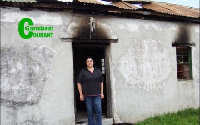 Truida Fourie staan in die deur van die erfenis-woning in B’Bos, waar sy gebore is, wat deur ‘n brand vernietig is.