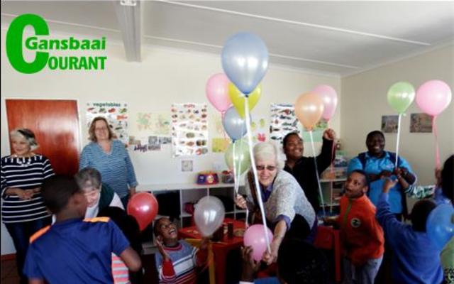 Die ballonne wat die Wacky Whalers Kwiltgroep na Gansbaai Elimhuis gebring het, het meer aandag as die lekkernye getrek. Voor is Olga Swanepoel, sameroeper, besig met die uitdeel van ballonne. 