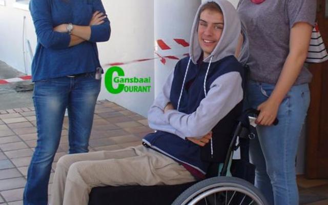 ‘n Spontane en glimlaggende Calvin Olivier in sy rolstoel tydens ‘n nootlegging wat ten bate van hom deur Laerskool Gansbaai gereël is. By hom is sy ma, Denise Olivier (links) en Mikayla Groenewald.