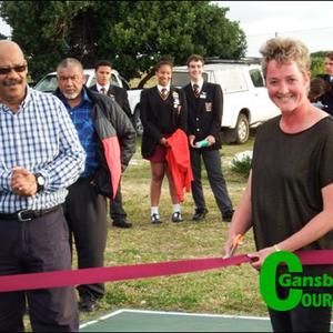 Kapt Gerda Groenewald, ondervoorsitter van Gansbaai Academia se Beheerliggaam, knip die seremoniële lint vir die amptelike opening van die netbalbaan. Die skoolhoof, mnr Tommy Wilson staan by haar.