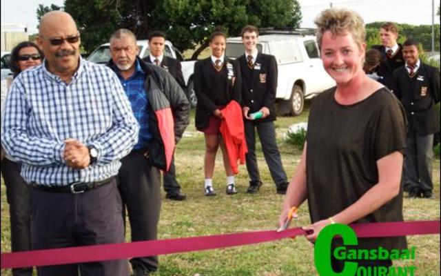 Kapt Gerda Groenewald, ondervoorsitter van Gansbaai Academia se Beheerliggaam, knip die seremoniële lint vir die amptelike opening van die netbalbaan. Die skoolhoof, mnr Tommy Wilson staan by haar.