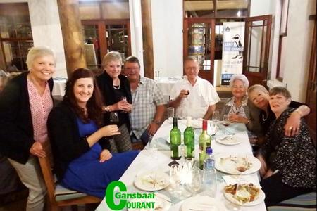 ‘n Groepie vrolike wynproewers tydens Gansbaai Wynproegilde se jaarafsluiting. Vlnr is om die tafel is Molley van der Colff, Nelleke van der Brugge, Diane Roodman, Theuns Roodman (voorsitter), Daan Oosthuizen (tesourier), Petro Oosthuizen, Sunet Heyns en Anita Botha.