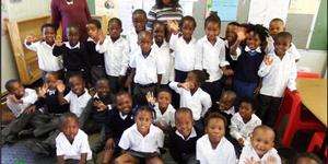 Masakhane Primary School se 52 graad R’e het ook aanvanklik aan hul kospakkies vasgeklou met die neem van die foto. Agter links is Ellen Pato (Gr R.a) en regs is Xoliswa Hoza (Gr R.b).