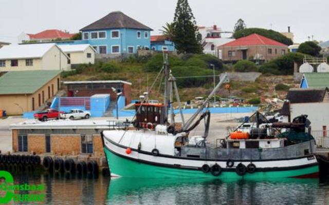 Die foto vertoon ‘n deel van die area in Gansbaai hawe waar ‘n man van Walvisbaai verdrink het. In die agtergrond kan die geskiedkundige “Blou Huis” bokant die hawe gesien word wat gedurende die naweek onder ‘n inbraak deurgeloop het.
