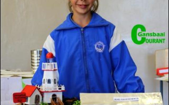 Adri Groenewald het ‘n hele dorpie ingehandig met dolosse op die voorgrond, die Danger Point Ligtoring en die Strandveld Museum.  Sy het Glenda Kitley, bestuurder by die Gansbaai Toerisme kantoor, gekies om ‘n onderhoud mee te voer.