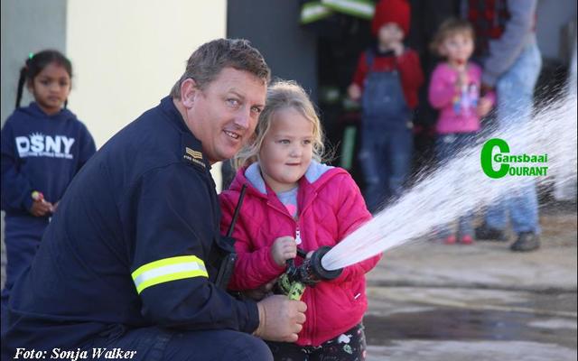 Gansbaai se nuut bevorderde senior brandweerman, Gallie Badenhorst het Woensdagoggend vir die kleuters van Kleine Gansies gewys hoeveel krag ‘n mens moet hê om ‘n brandslang vas te hou.  Die 5-jarige Layla Wessels kry dit sowaar reg.  