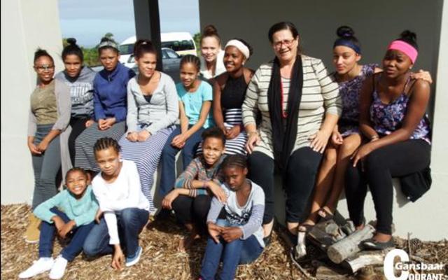 Die Herberg Kinderhuis se huismoeder, Bettie Thomas (3de van regs), word hier omring deur Huis E se dogters op die stoep van die gastehuis terwyl hulle vir hul Sondagmiddagmaal wag.