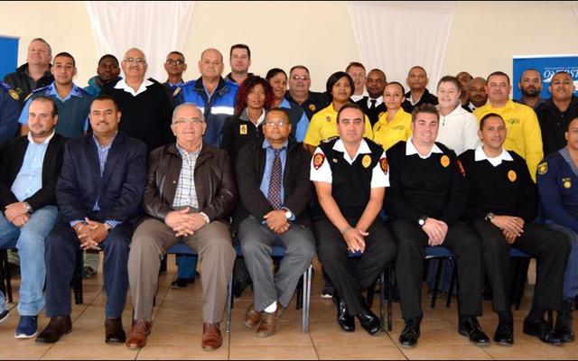 The Overstrand Fire Department recently hosted an end of fire season debriefing session at the Pringle Bay Community Hall. Front fltr Overstrand’s Cllr Fanie Krige (Kleinmond), Cllr Grant Cohen (Kleinmond), Neville Michaels (Director:  Protection Services), Coenie Groenewald (Municipal Manager), Cllr Arnie Africa (Portfolio Head:  Protection Services), Lester Smith (Chief:  Fire, Rescue and Disaster Management), Marlu Rust (Snr Disaster Management Officer) and Angelo Aplon (Ass Chief:  Fire, Rescue and Disaster Management). The large group at the back included officials of the Overstrand Traffic, Fire and Law Enforcement, Overberg District Municipality, Greater Overberg Fire Protection Association, City of Cape Town Fire and Rescue, CapeNature, NCC Environmental Services and Provincial Traffic.