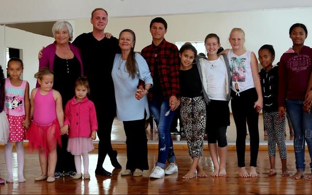 Christopher staan hier saam met Cynthie Aggenbag (links van hom) en Lynette van Wyk (regs van hom) omring deur ‘n groep opgewonde kinders. 