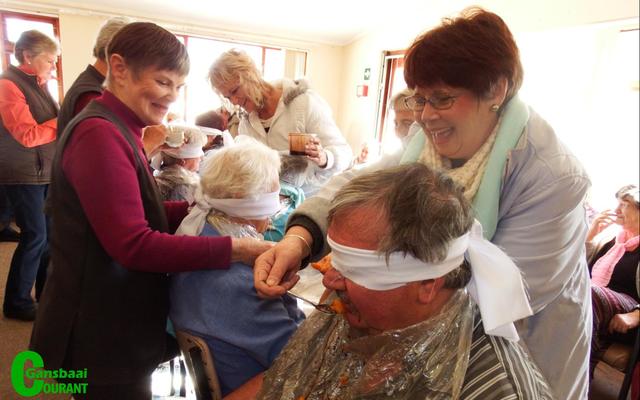 Selfs John van Rooyen, die bestuurder van HaS is geblinddoek vir Goue Hande se item.  Met voorskote gepantser moes die deelnemers raai wat hulle gevoer word.  Die toeskouers het geskaterlag oor die petalje.  Anita Botha (links) en Marie de Jager besig om John se smaakvermoë te toets.