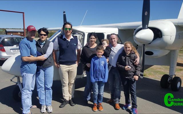 Walvisbesigtiging vanuit die lug is ‘n onvergeetlike belewenis. Hiervan kan dié bevoorregte groepie getuig nadat hulle die naweek saam met Overberg Aviation gevlieg het.  Links staan Phillip en Heidi Rozekrantz, terwyl Christiaan en Melody du Plessis regs saam met hulle kinders staan. By Kleinbaai-hawe is dit ook soggens vroeg al ‘n bedrywigheid soos wat toeriste vanuit al die wêrelddele aankom om op die gewilde boottoere te gaan.  Stappers en rotsklimmers geniet veral die staproetes en grotte by De Kelders.  Die Danger Point ligtoring is een van die gewilde toeriste-aantreklikhede op die oomblik.  Lorraine de Klerk, ‘n stapgids vertel dat sy op 1 dag al 15 walvisse in Walkerbay gesien het.  “Om ‘n walviskoei in die oog te kyk wat besig is om haar kleinding te soog, is onbeskryflik.” 